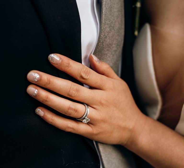 Bride wears clear diamond engagement ring and slightly glittered nail varnish 