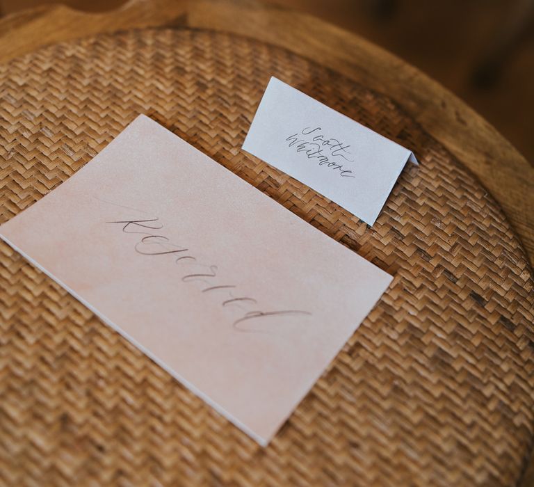 White place name and pink reserved sign on rattan seat of wooden chair for summer wedding ceremony at Primrose Hill Farm