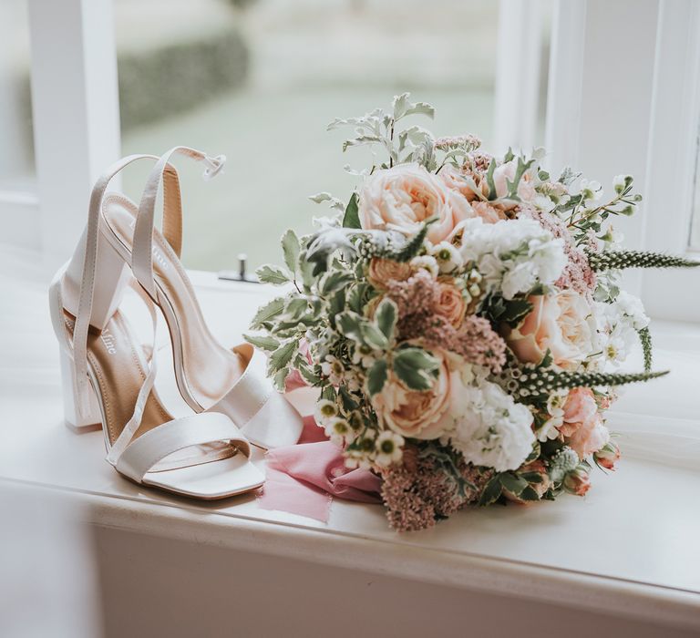 White strap block heels on windowsill next to white and blush pink bridal bouquet with green foliage for Primrose Hill Farm summer wedding