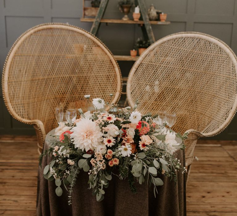 Sweetheart wedding table complete with wicker chairs and floral bouquet to the front