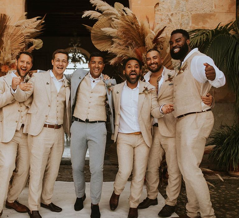 Groom stands with his groomsmen who wear sandy coloured suits and white shirts