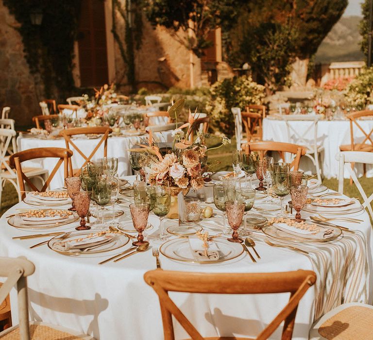 Outdoor wedding reception complete with coloured glassware and floral bouquets