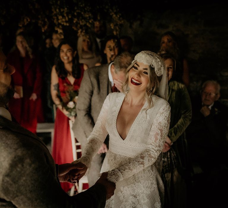 Happy bride in a lace wedding dress with plunging neckline and long sleeves 