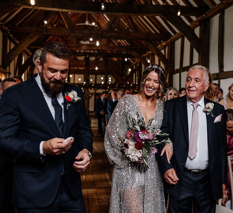 Father of the bride walking his daughter down the aisle in a grey sequin wedding dress at Tithe Barn, Loseley House wedding venue 