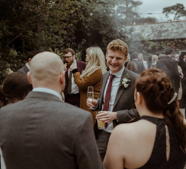 Wedding guests stand outdoors on wedding day