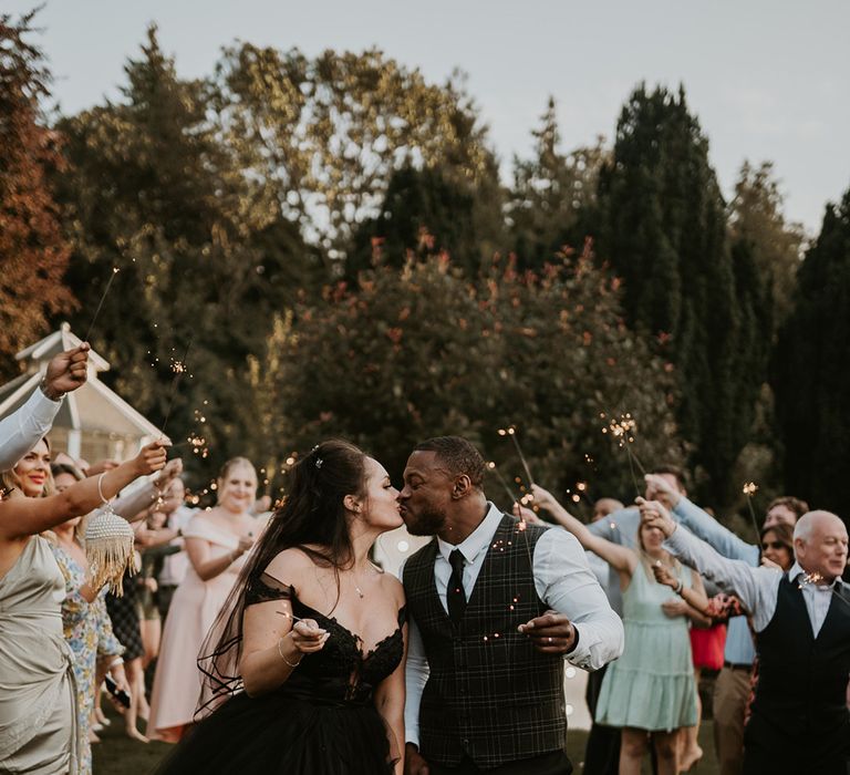 Bride & groom hold sparklers surrounded by wedding party 