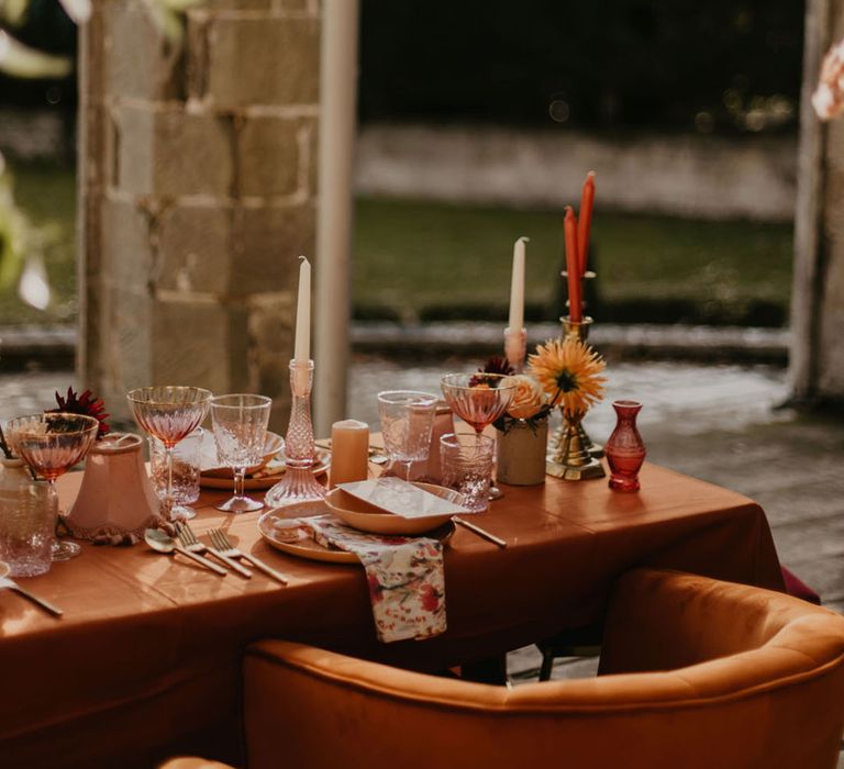 blush pink, orange, peach and coral wedding table decor with glass candlesticks, tableware and linens 