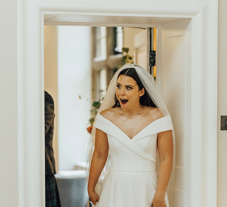 Bride in an off the shoulder Suzanne Neville wedding dress and long veil seeing her wedding reception for the first time 