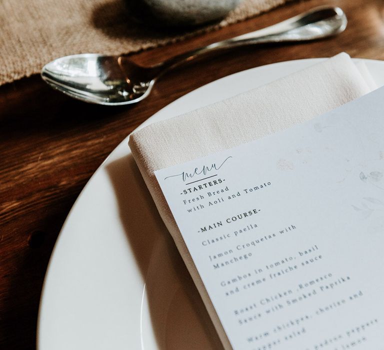 White menu card with flower design for wedding with silver cutlery and cream napkins