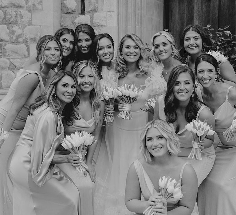 Bride poses with her bridesmaids as they all hold white tulip bouquets