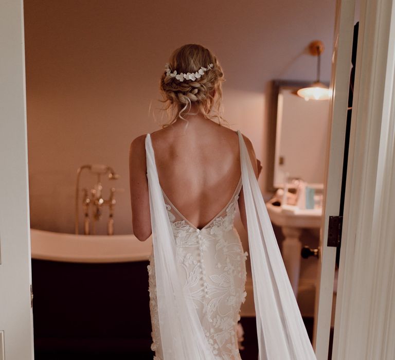 Bride in floral lace wedding dress with open back and white flower hair accessory 