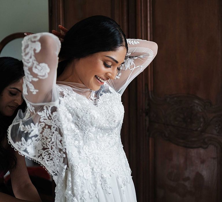 Bride is zipped up into lace illusion wedding dress with long sleeves 