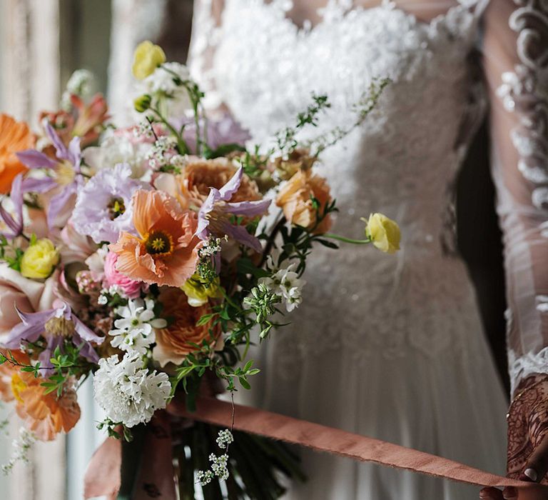 Bride holding colourful purple and orange wedding bouquet wearing lace white wedding dress