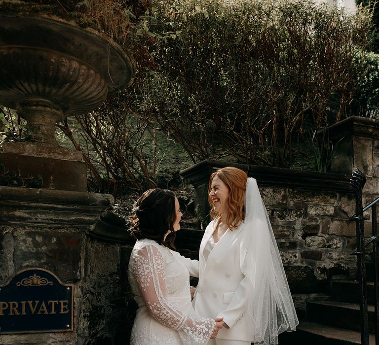 Brides laugh with one another outdoors during their Edinburgh wedding 