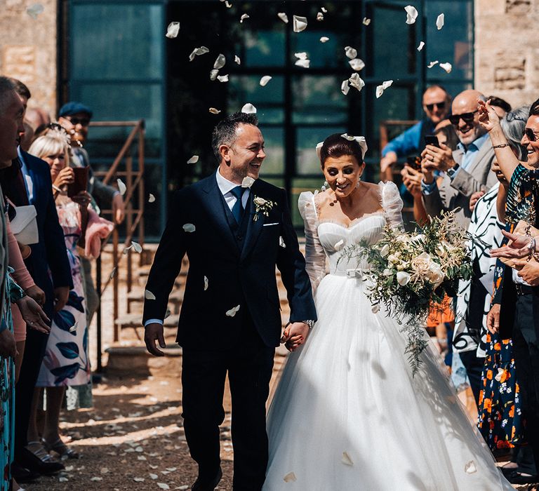 Bride and groom have white rose petal confetti exit from their rustic wedding ceremony 