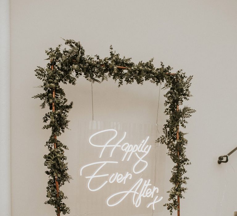 'Happily Ever After' white neon sign with foliage decor