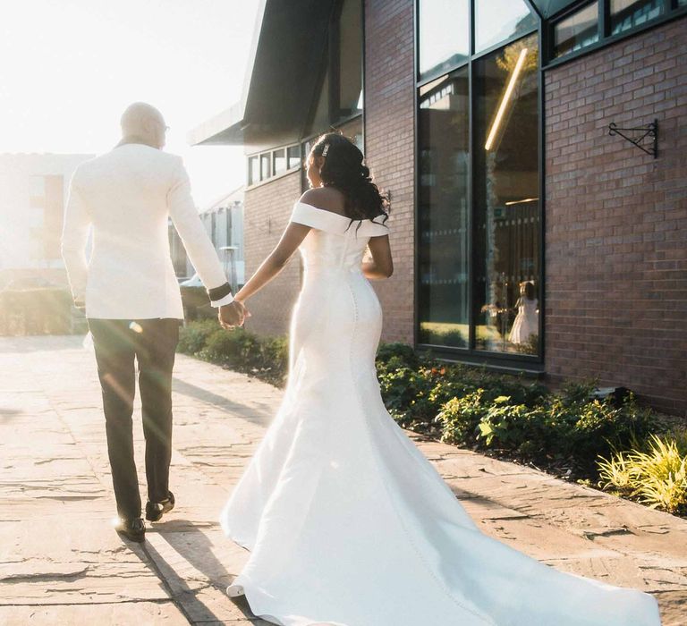 Bride & groom walk outdoors as the sun shines around them after wedding ceremony at the Edgbaston Park Hotel