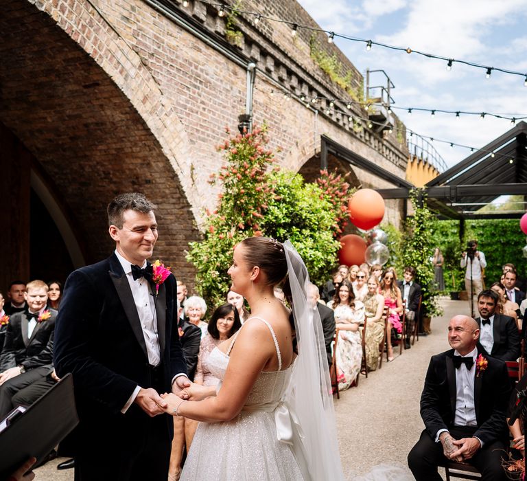 Bride & groom stand outdoors at the 100 Barrington during ceremony for colourful orange and pink wedding 