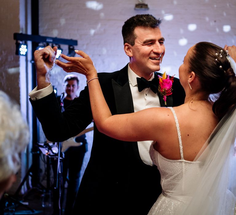 Bride and groom dance during reception as bride wears her hair in a bun complete with pearl hair accessories 