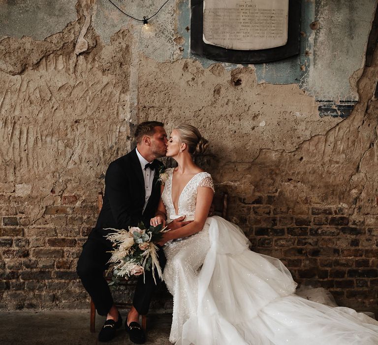 Bride & groom kiss at rustic The Asylum wedding venue after ceremony in London