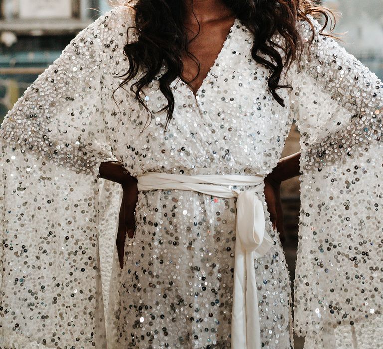 Bride in a white and silver sequin wedding dress with a white ribbon belt and oversized sleeves 