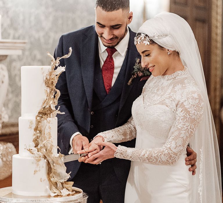 Bride and groom cut their wedding cake with a shiny gold 3D design 