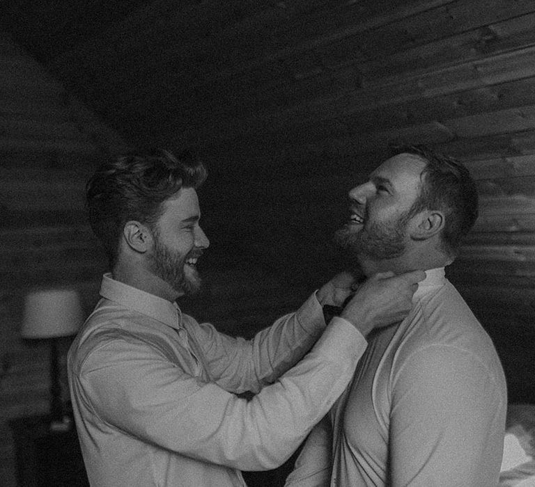 Grooms help each other get ready for their wedding day 