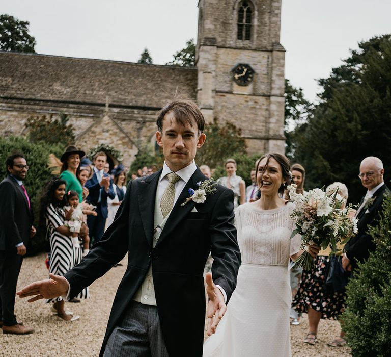 Bride and groom post ceremony walking the grounds of Kelmarsh Hall surrounded by wedding guests