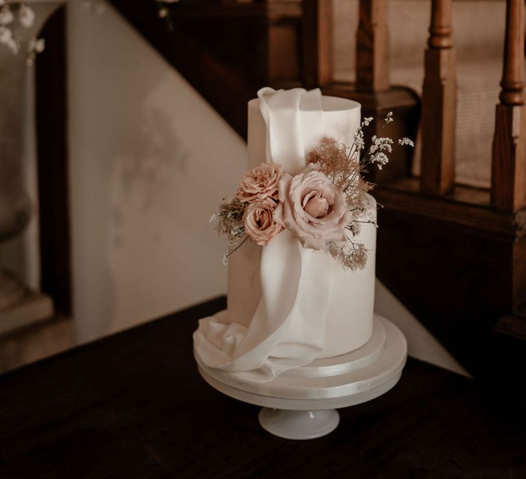 Classic white iced two tier wedding cake with ribbon and pink flowers for a country house wedding 