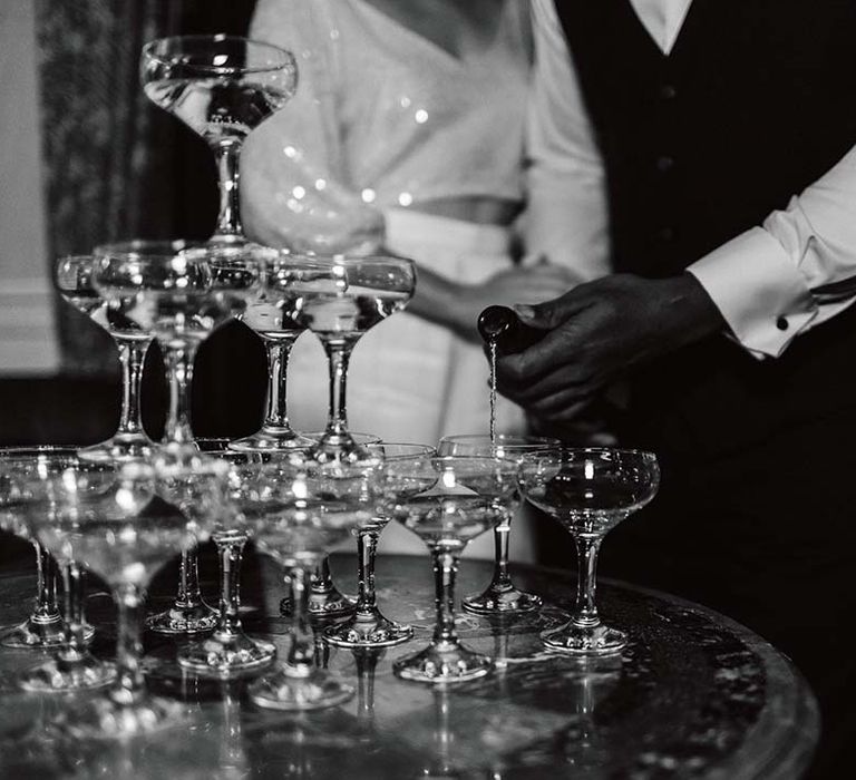 Bride and groom topping up champagne tower at stylish winter wedding 