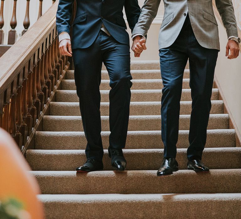 The grooms walk hand in hand down the stairs as they prepare to enter their wedding ceremony together 