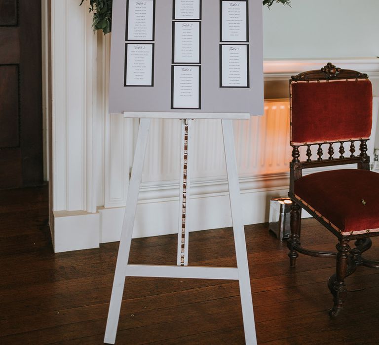 Grey and white wedding seating chart with decorative foliage 