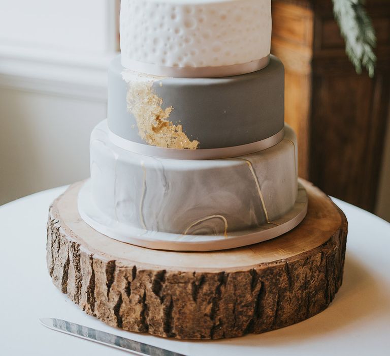 Four tier grey, white and gold wedding cake with each layer decorated differently with a black personalised cake topper 