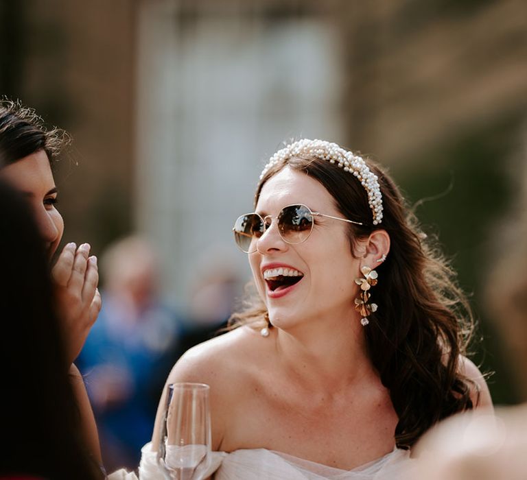 Bride wearing sunglasses with pearl headband and statement flower earrings 