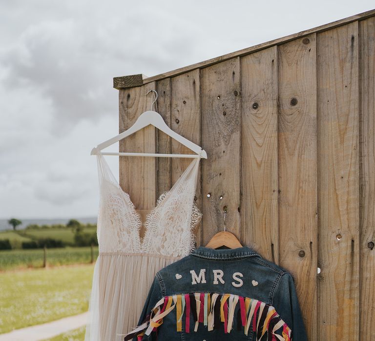 Personalised denim jacket complete with colourful fabric beside scalloped lace wedding dress