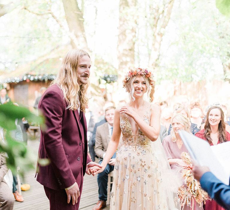 Bride wears sequin star wedding dress and stands beside her groom in maroon suit 