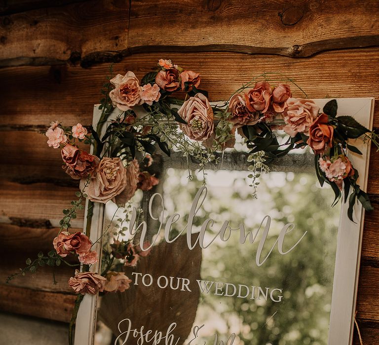 Mirror wedding welcome sign with pink wedding flower decorations with a white wooden frame 