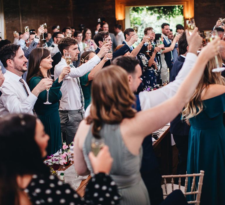 All the wedding guests lift their glasses in a toast for the bride and groom on their wedding day