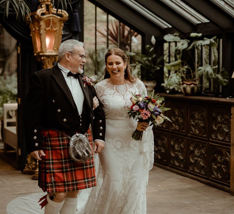 Bride in boho lace Rue De Seine wedding dress being walked down the aisle by the father of the bride in a Scottish kilt at Newton Hall