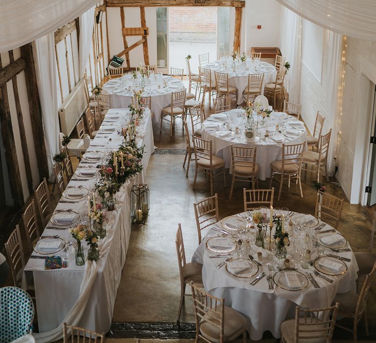 Dove Barn Weddings reception room with white drapery and fairy lights with a classic white tablescape and pastel flowers 