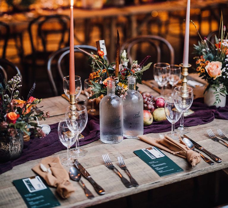 Dark green wedding menu with burgundy table runner with peach and purple taper candles with autumnal flowers for November wedding 