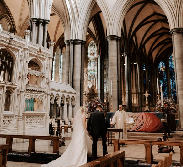 Salisbury Cathedral wedding ceremony with the bride and groom standing at the altar with the priest leading the ceremony 