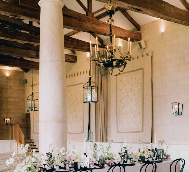 Settrington Orangery reception room with Notan inspired wedding tablescape consisting of light pink wedding tablecloth, white poppies, light pink Persian buttercups, baby's-breath and foliage centrepieces, black artistic candlestick holders, white tapered candles, black crockery and monochrome wedding stationery 