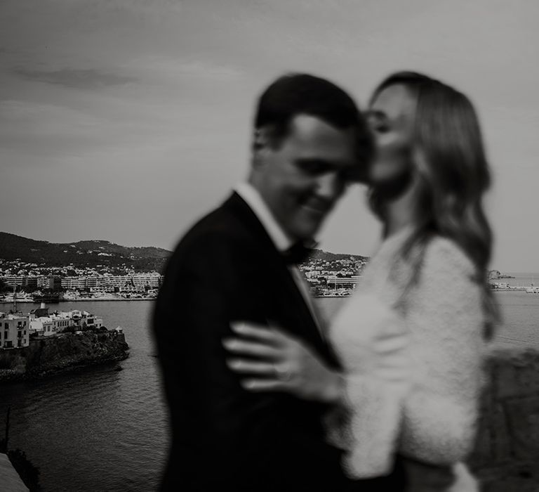 Ibiza destination wedding with bride kissing her groom on the head with island views in the background