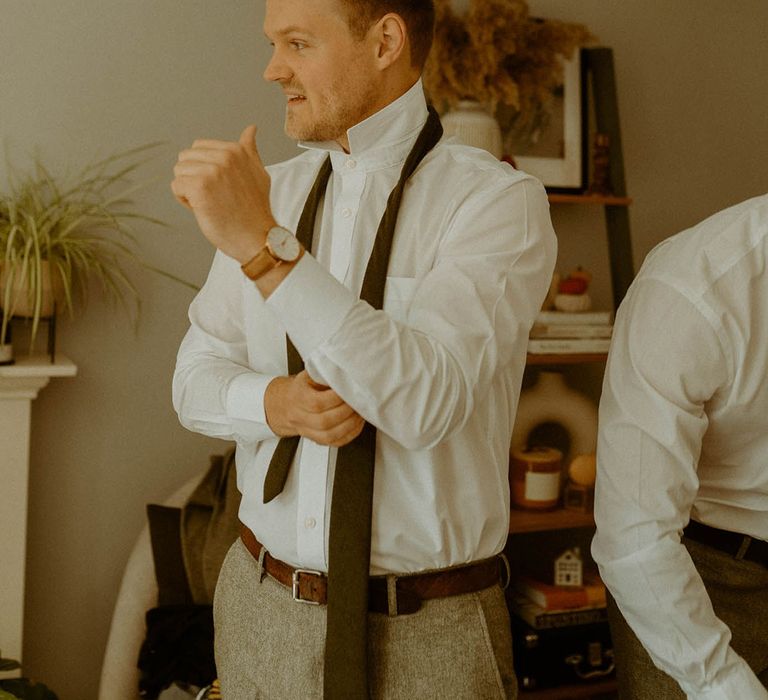 Groom gets ready for the wedding day putting on his cufflinks and ties 