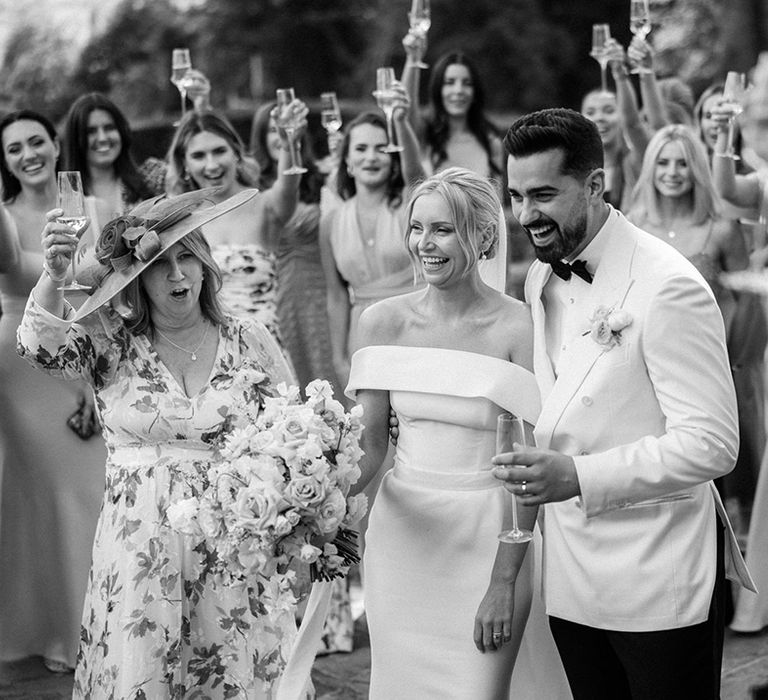 The wedding guests all raise a toast to the bride and groom at their traditional and classic wedding 