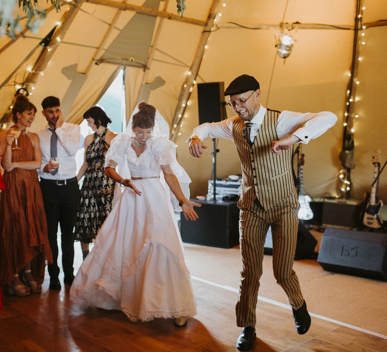 Bride in ruffle bridal separates dances with groom in pinstripe suit at tipi wedding