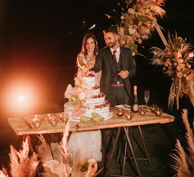 bride and groom cutting the semi naked wedding cake laden with fruit at tenuta il cigno wedding 