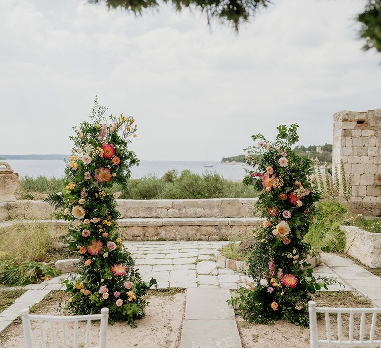 Historic wedding venue in Hvar Croatia with coral, pink and blush wedding flower columns at altar