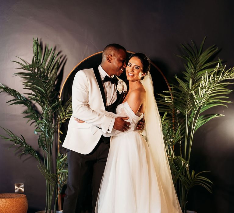 Bride in white off-the-shoulder wedding dress poses at Crumplebury wedding with groom in black and white tuxedo